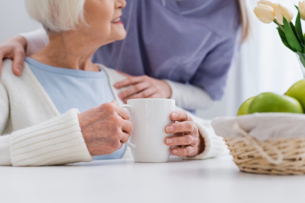 Close-up cropped photo of younger woman with hands on older woman holding mug