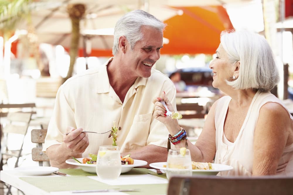 Smiling senior couple eating at outdoor table at restaurant