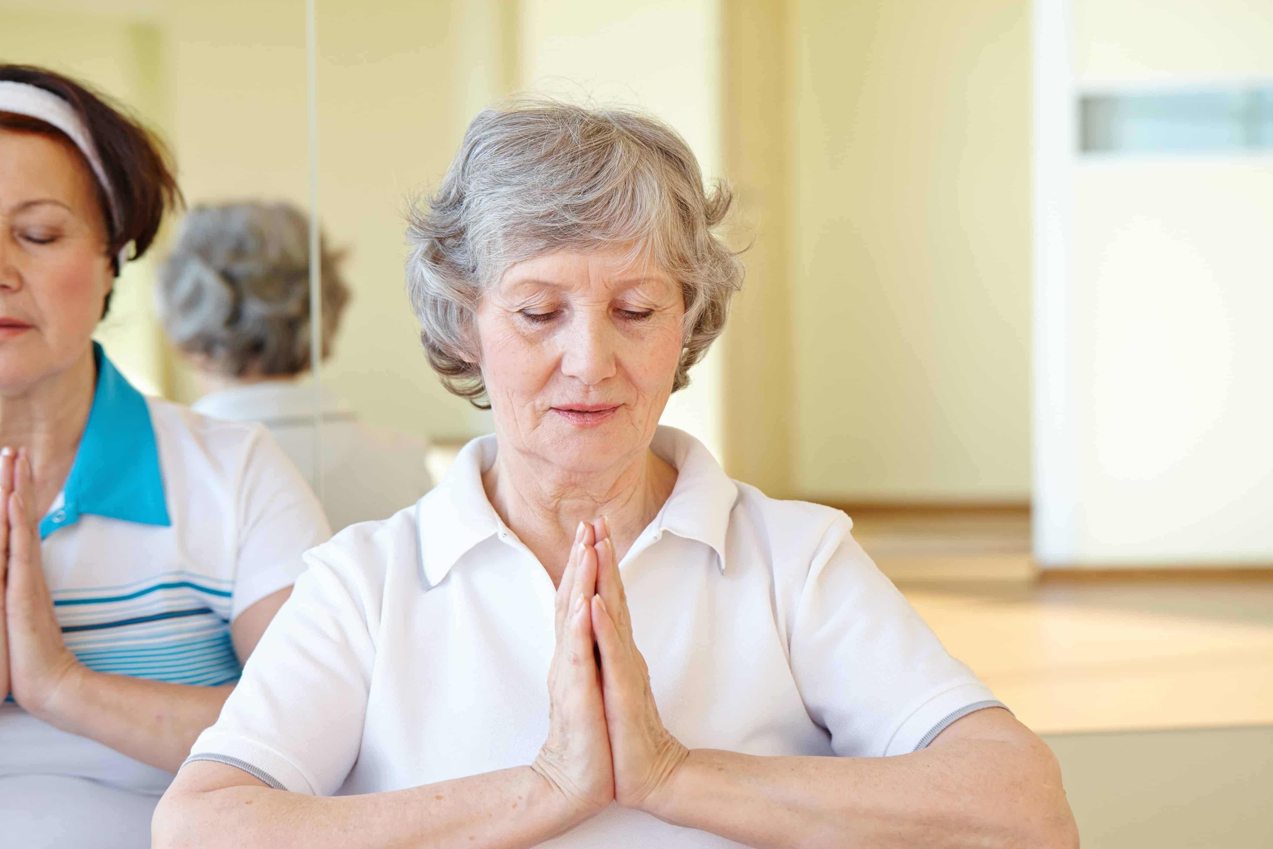 Senior woman practicing yoga, eyes closed and hands pressed together