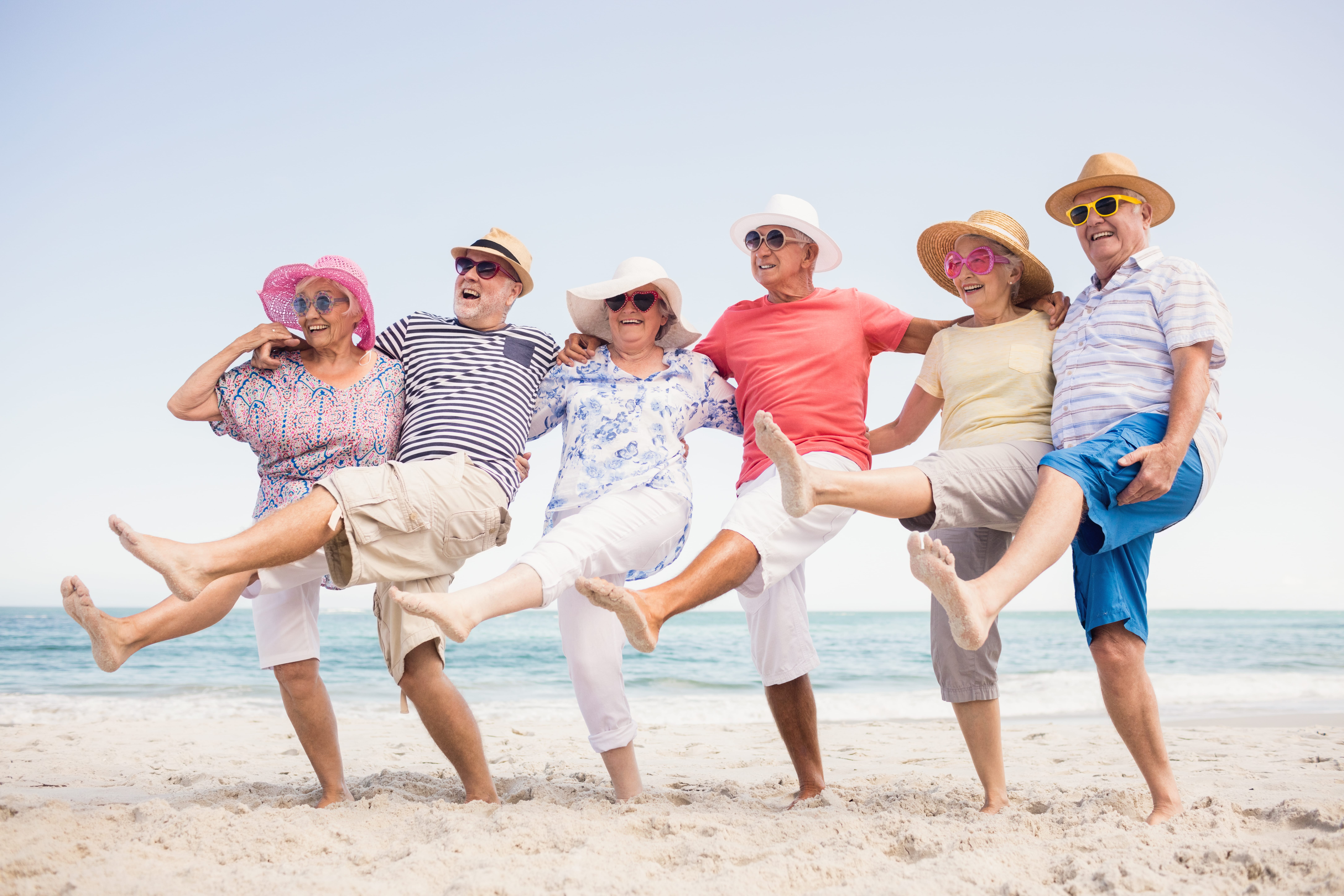 Group of seniors having fun on the beach, kick line