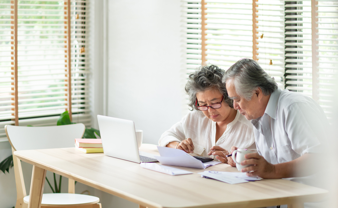 Stressed Asian Senior Couple using calculator and calculate family budget, Debts, monthly expenses in home during Financial economic crisis. Senior man and woman looking at account book, bill, passbook, receipt and laptop computer on table.