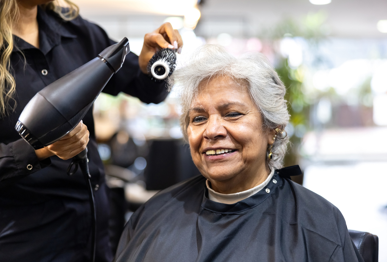 Happy Latin American senior woman smiling at the hairdressers while getting a haircut - beauty concepts